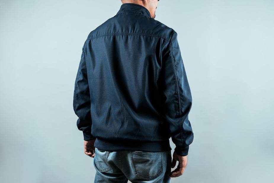 Back view of a navy sports jacket made of lightweight waterproof polyester with soft mesh lining.