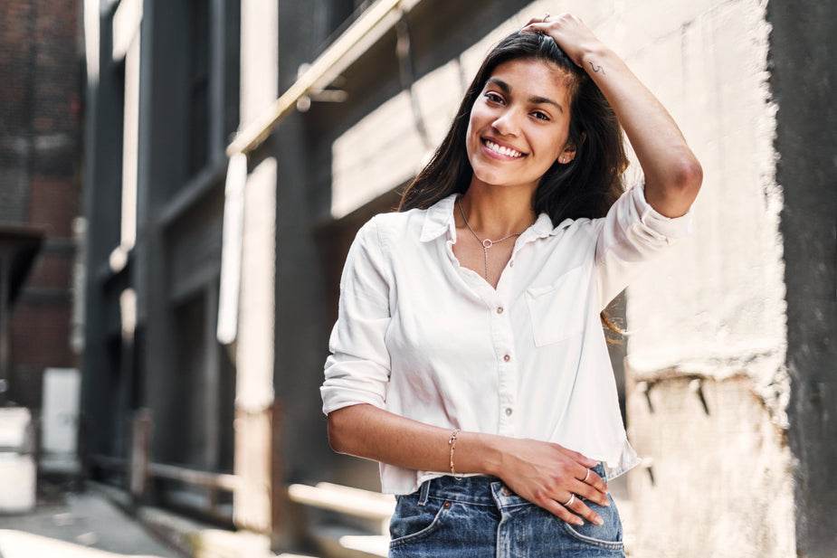 Smiling woman wearing white cotton shirt with front pocket and small buttons outdoors