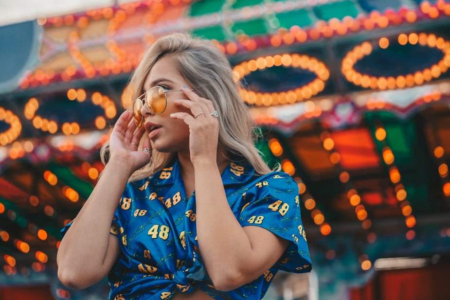 Woman wearing blue silk summer top with number pattern and short sleeves at carnival lights background