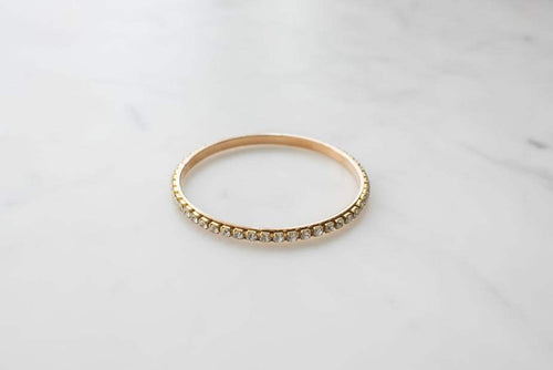 Gold bangle bracelet studded with jewels on marble background