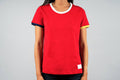 Women's red sports tee with colorful sleeve details and white pocket